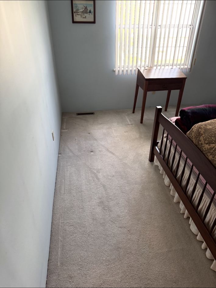 Bedroom cleared after junk removal, empty carpet and open floor